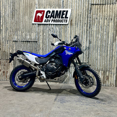 A Yamaha 700 Tenere motorcycle with an Enduro bend high exhaust system by Camel ADV Products, displayed indoors with a logo in the background.